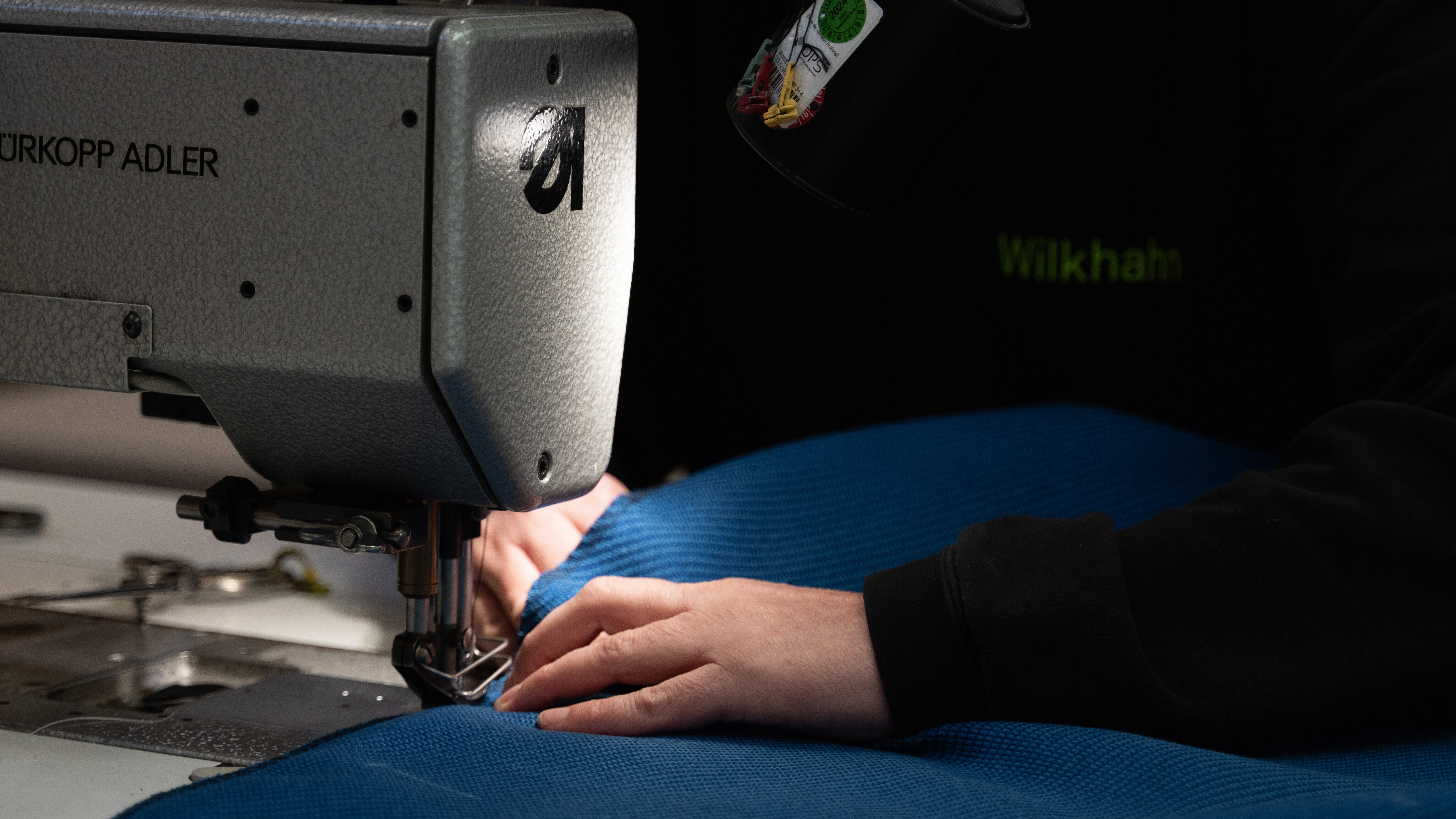 A close-up of someone sewing the upholstery together. The upholstery is blue.