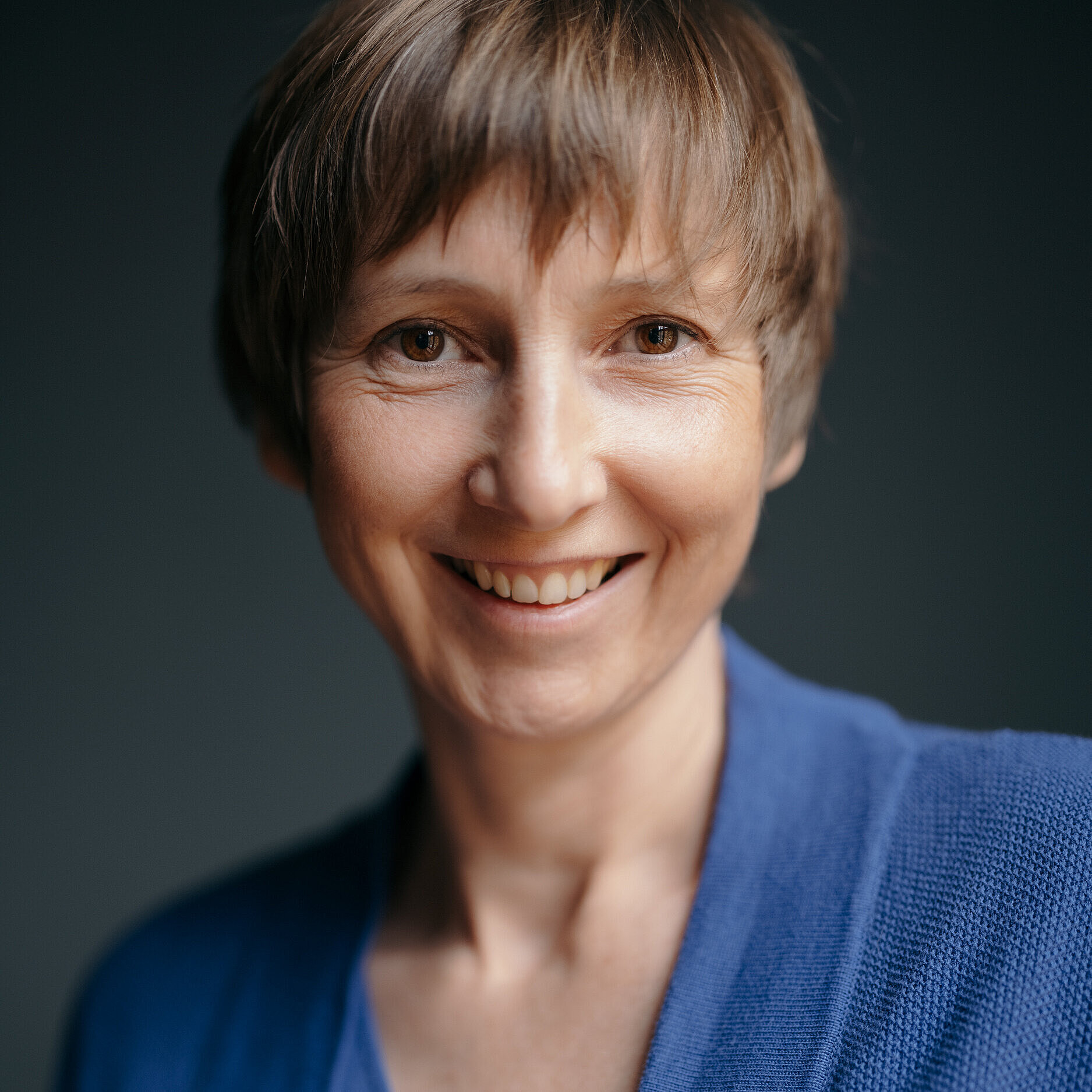 The portrait depicts a woman in a warm, natural lighting setting. It is a professional business portrait with no apparent connection to Wilkhahn. The focus is on personality, authenticity, and approachability.