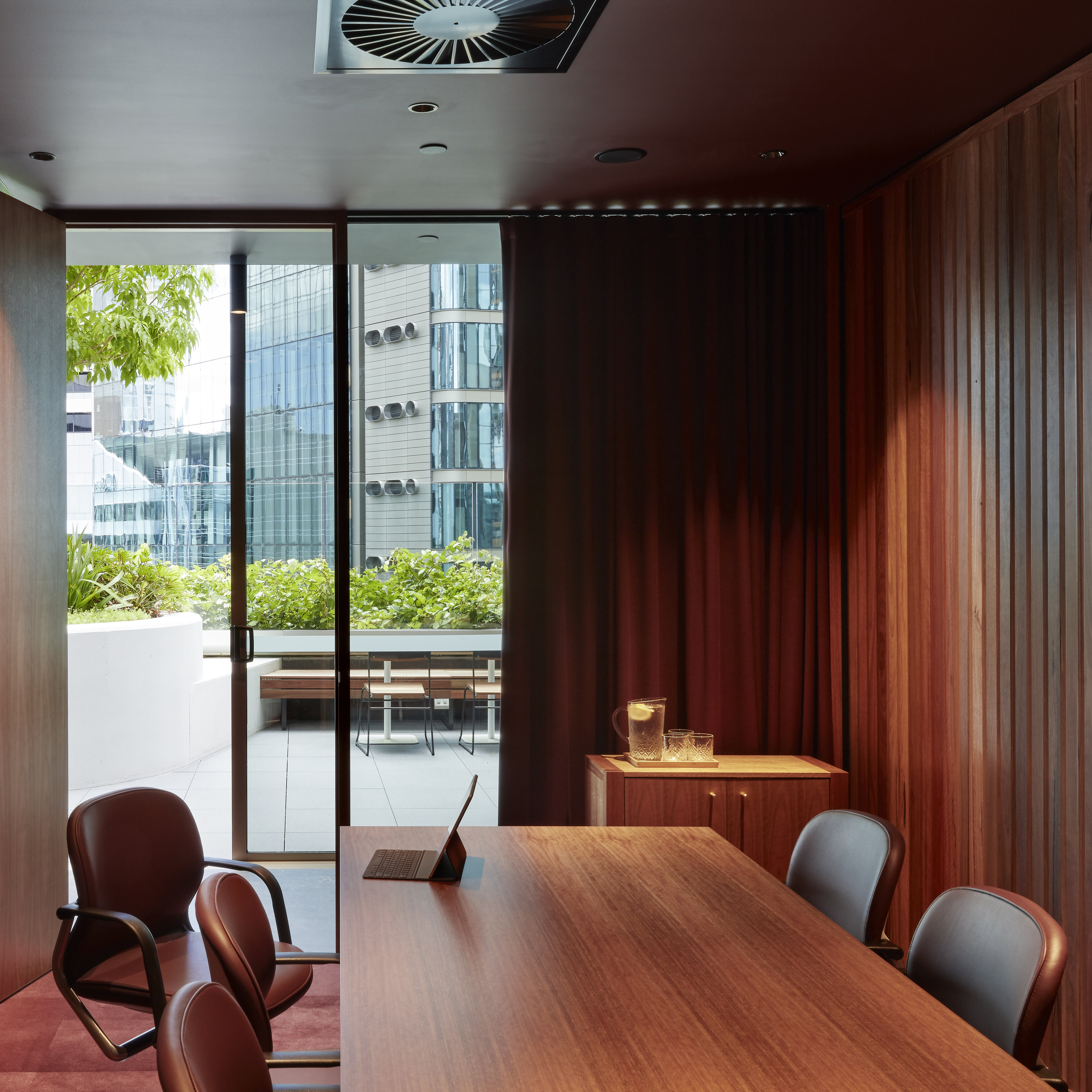 This space combines dark wood surfaces, a large conference table, and FS chairs. The glass front opens the space onto the terrace, creating an exclusive, modern work environment.