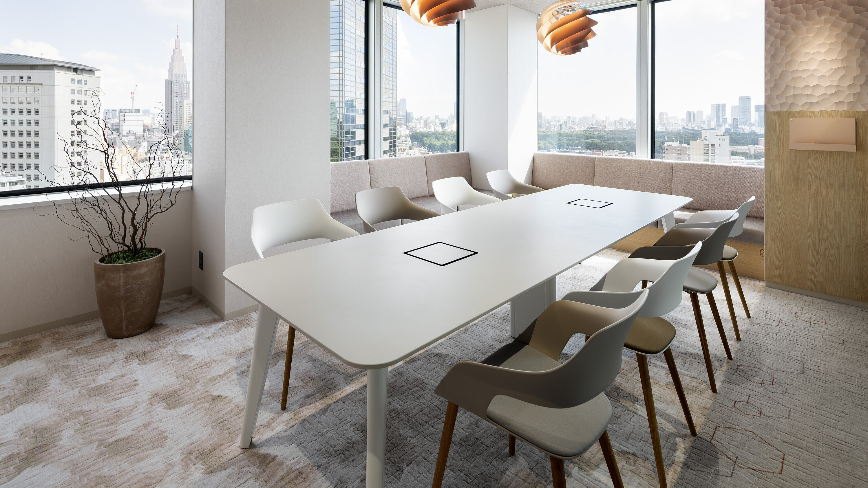 Occo chairs with beige or white seat shells are arranged around a long white conference table. The conference room has many windows and is generally decorated in shades of beige.