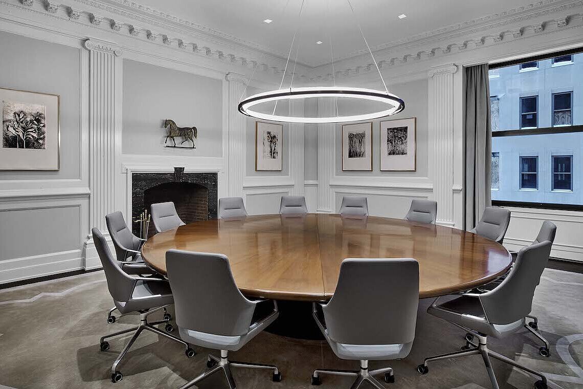 A conference room with a round table and light gray Graph chairs with low backrests.