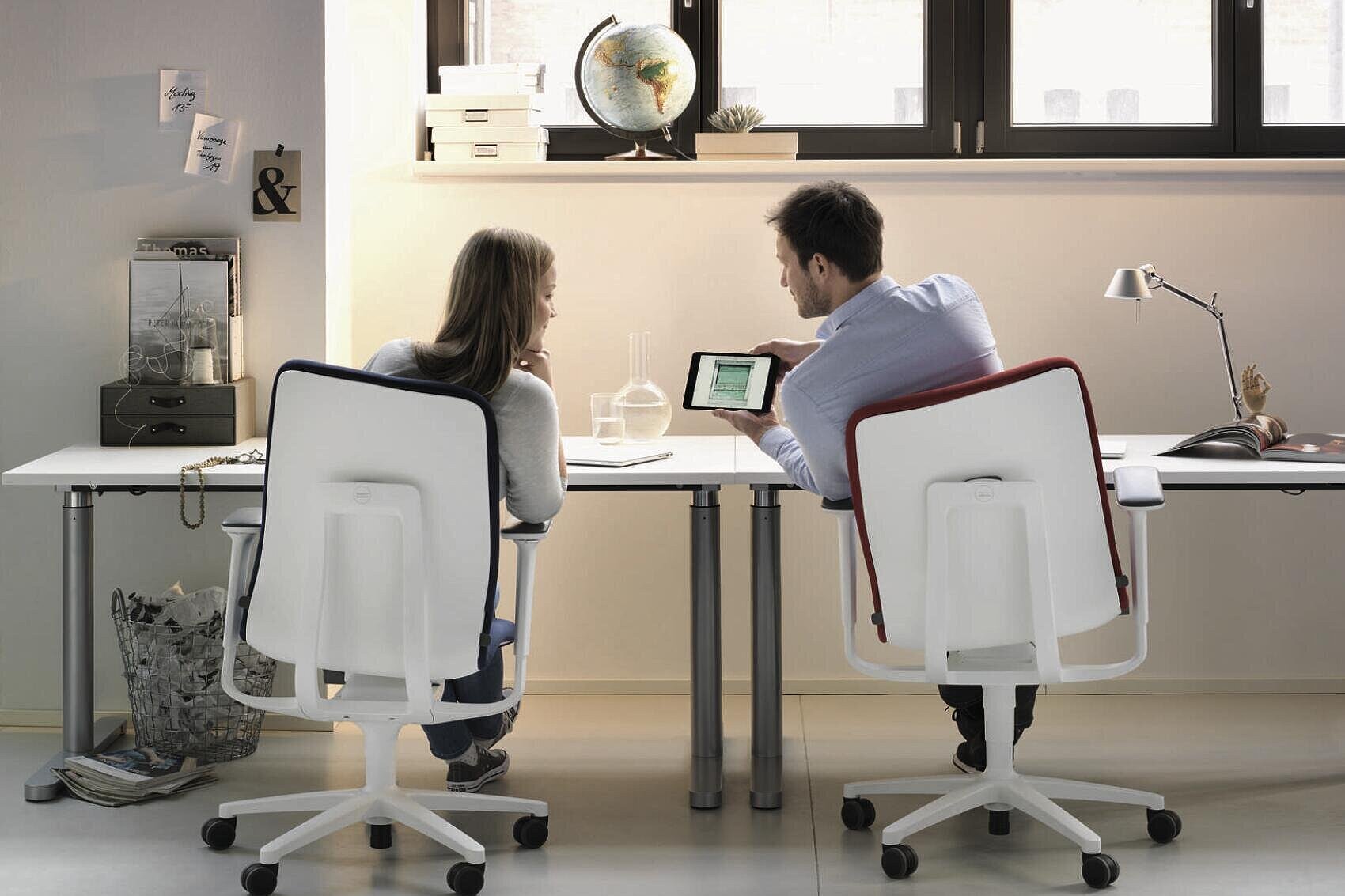 AT swivel chairs in modern office environment, two people collaborating at workstation