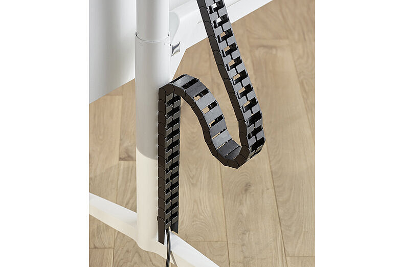 A close-up of a black cable system on a white Timetable table leg.