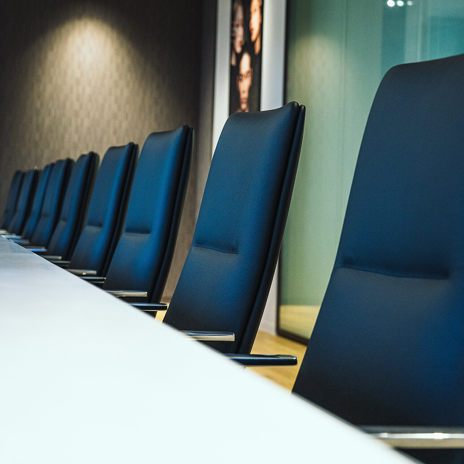 A close-up of Sola conference chairs in black leather. They are arranged around a white table in a conference room.