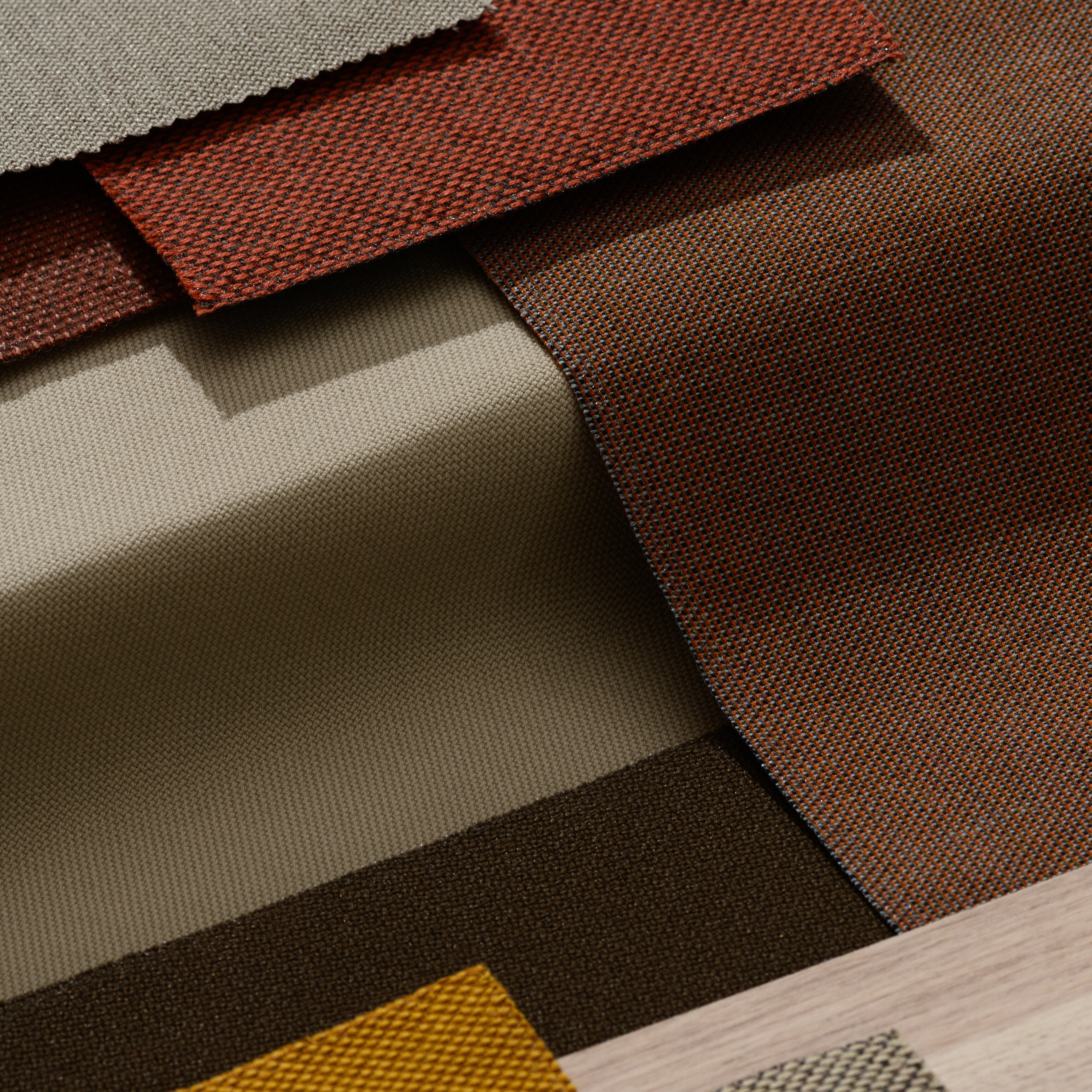 Natural, earthy tones such as ochre, brown, beige, and wood tones dominate here. The fabric textures have an organic feel and create a calm, nature-inspired atmosphere.