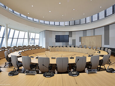 The photo shows gray Intra chairs arranged in circular rows. There is a microphone at each seat.