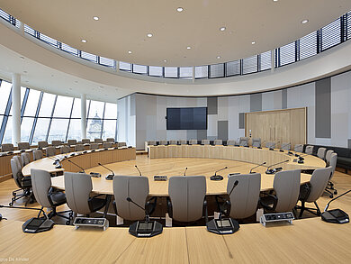 The photo shows gray Intra chairs arranged in circular rows. There is a microphone at each seat.