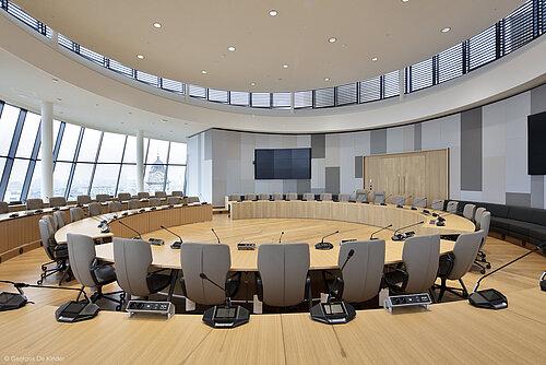 The photo shows gray Intra chairs arranged in circular rows. There is a microphone at each seat.