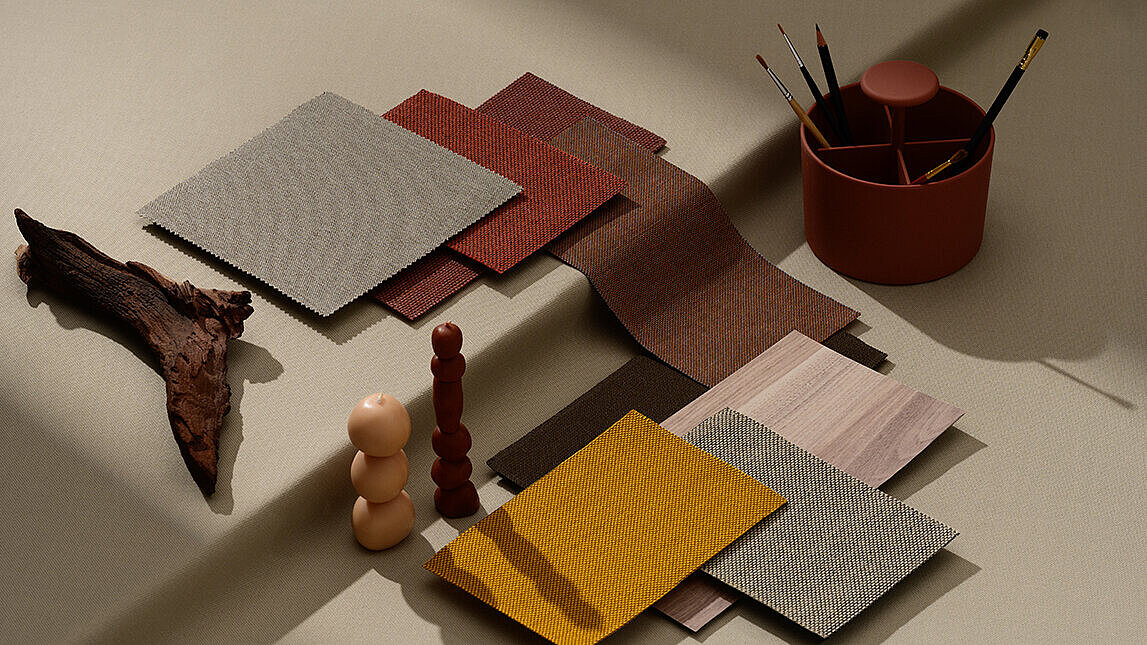 Various fabrics and surfaces in earthy tones are arranged together to serve as a mood board. Objects such as a piece of wood, candles, and a pencil holder in matching colors are also visible.