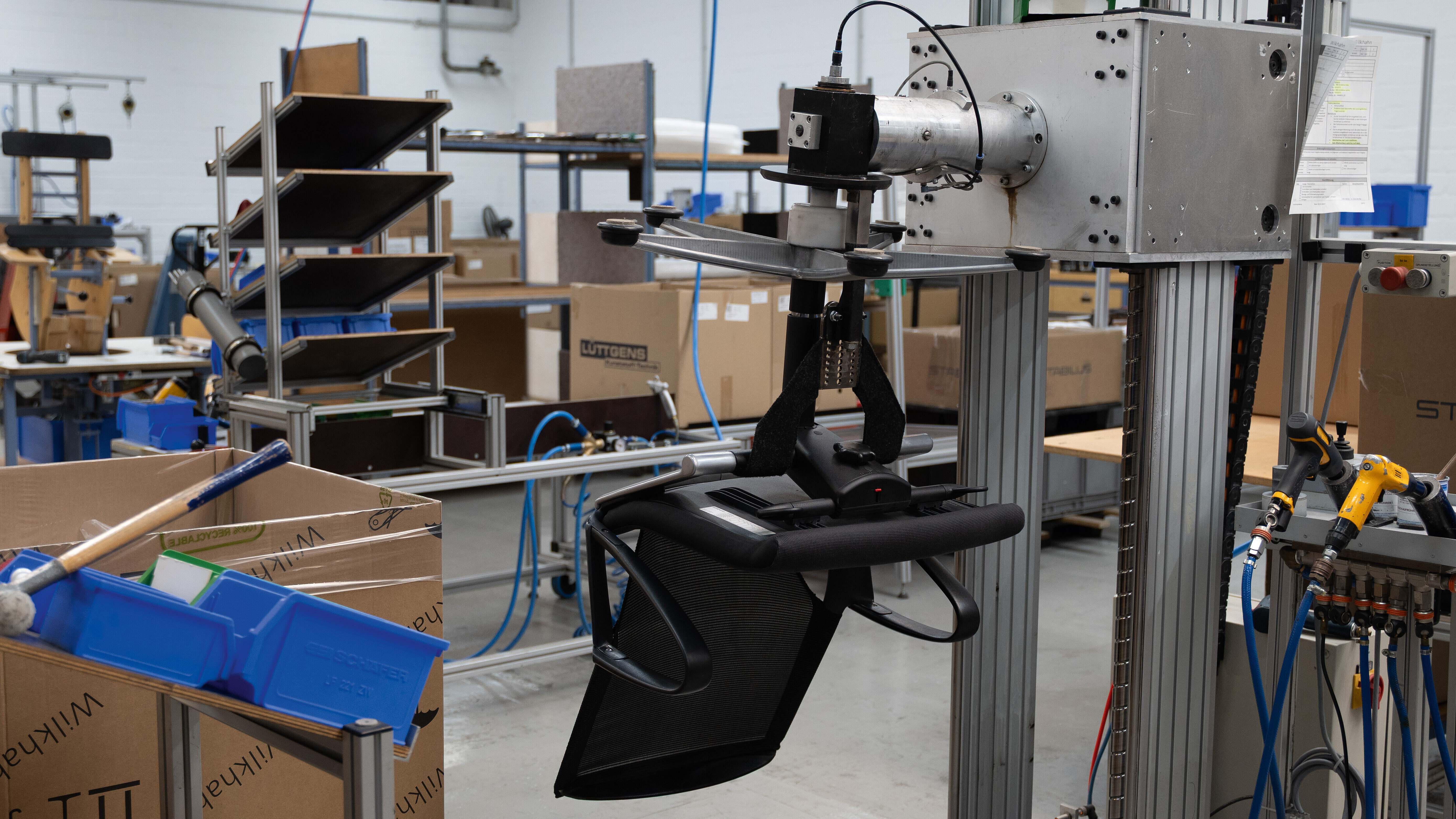 A Modus chair is mounted in a support bracket designed to assist with installation. The assembly hall can be seen in the background.