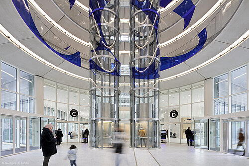 An entrance hall with two glass elevators visible in the center. The entrance hall has several noticeable entrance doors.