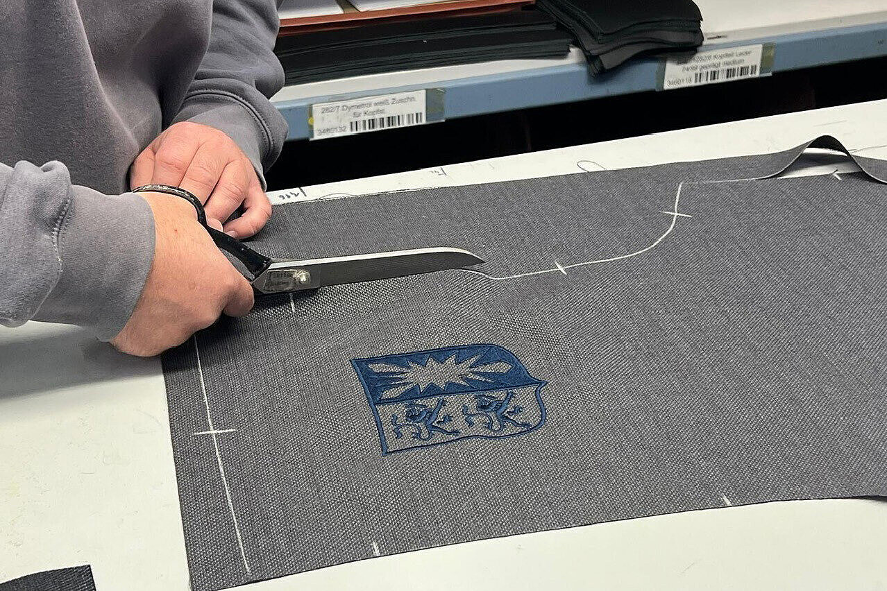 It is a close-up showing the gray fabric being cut out to form the Kiel coat of arms.
