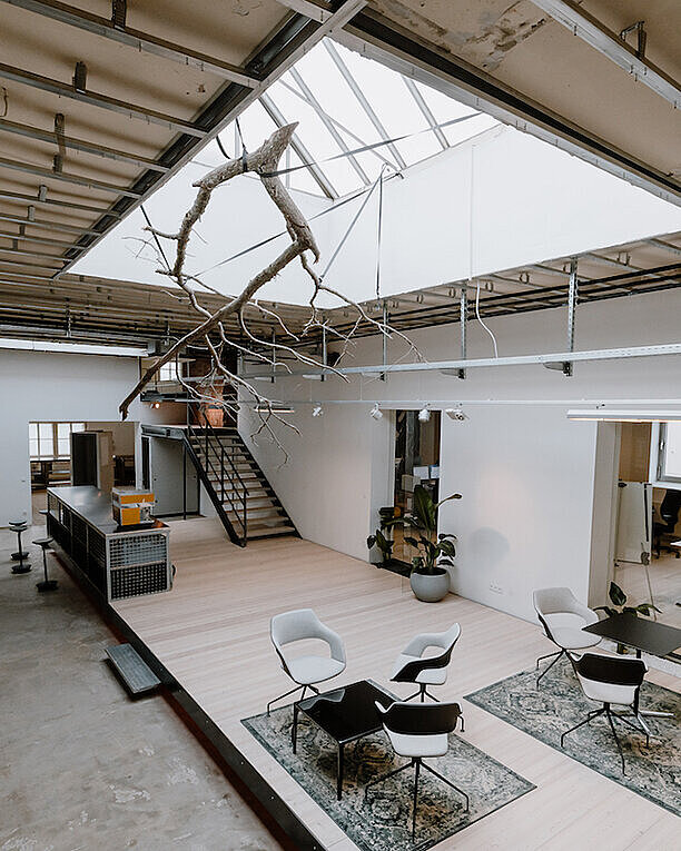 An entrance hall featuring various Wilkhahn products, such as Occo chairs and tables, as well as Stitz. The entrance hall is open and bright, and you can see the adjacent offices.