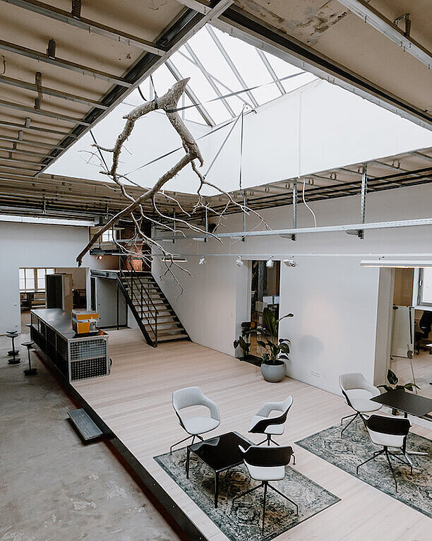 An entrance hall featuring various Wilkhahn products, such as Occo chairs and tables, as well as Stitz. The entrance hall is open and bright, and you can see the adjacent offices.