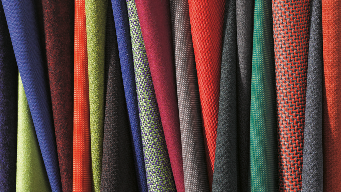 Various fabrics in a wide variety of colors are laid out side by side.