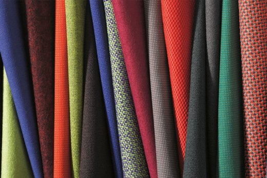 Various fabrics in a wide variety of colors are laid out side by side.