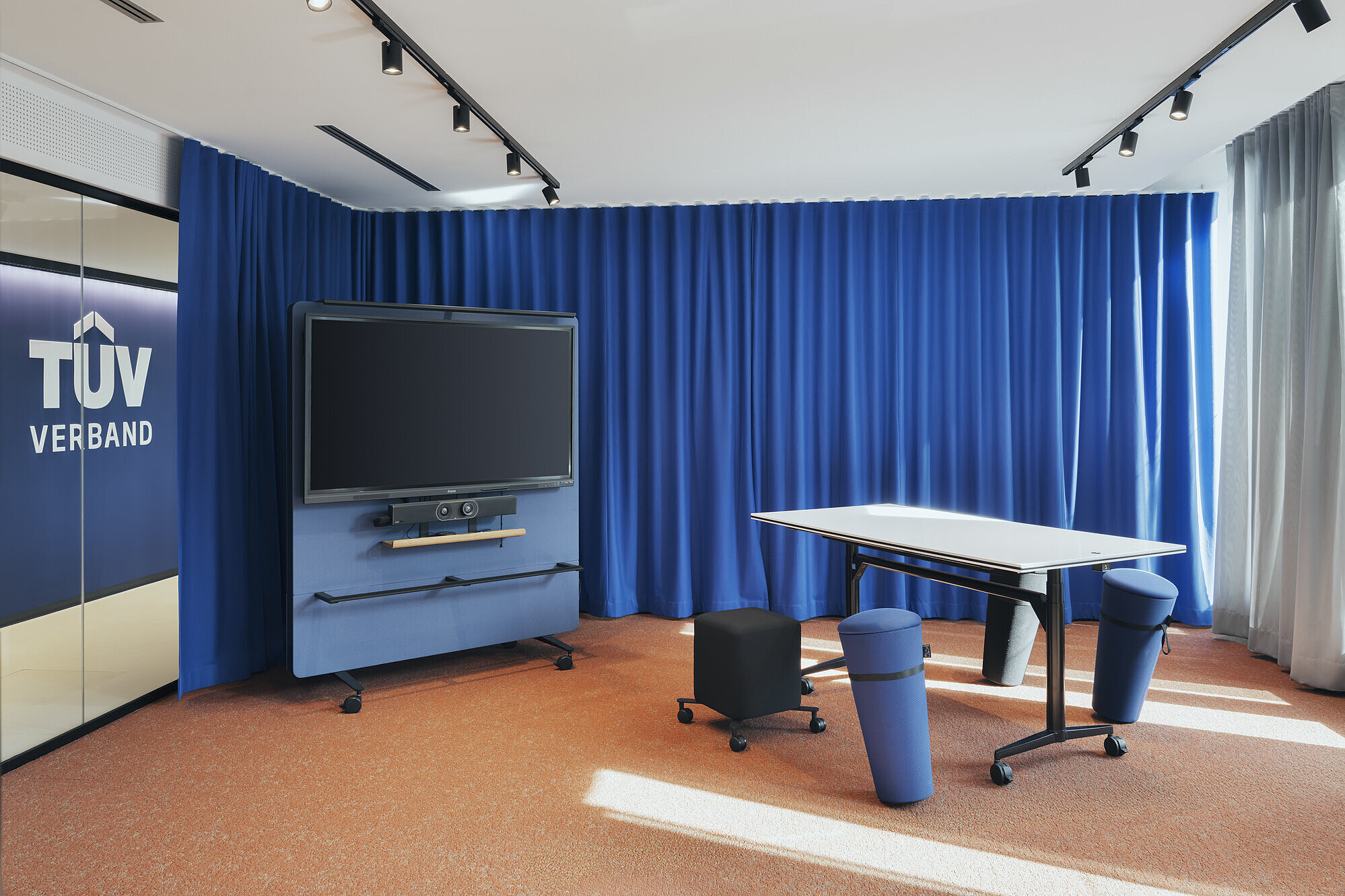 The space features flexible workshop furniture, including a fold-out timetable used for agile work formats. The mobile stools and the large multifunctional display facilitate spontaneous teamwork. The strong colours, mainly blue, create an energetic work atmosphere.