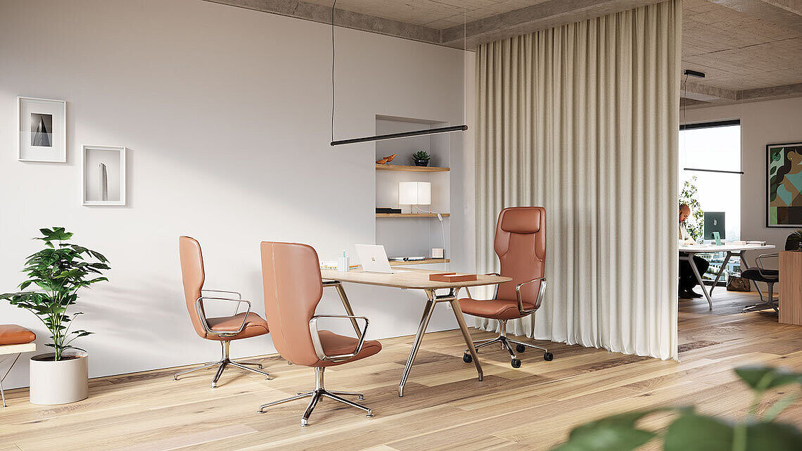 The bright office space features several Wilkhahn Intra Highback chairs in a warm cognac tone. Their high backrests, sleek chrome frames, and ergonomic design lend the room an exclusive, sophisticated look. The appealing combination of wood, fabric, and metal creates a welcoming, modern work environment. 