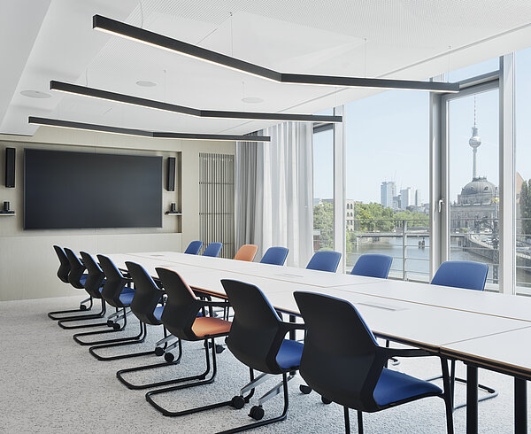 The large conference room is furnished with a row of Metrik cantilever chairs, shown here in blue and orange. The large window wall in the background provides plenty of natural light and a view.