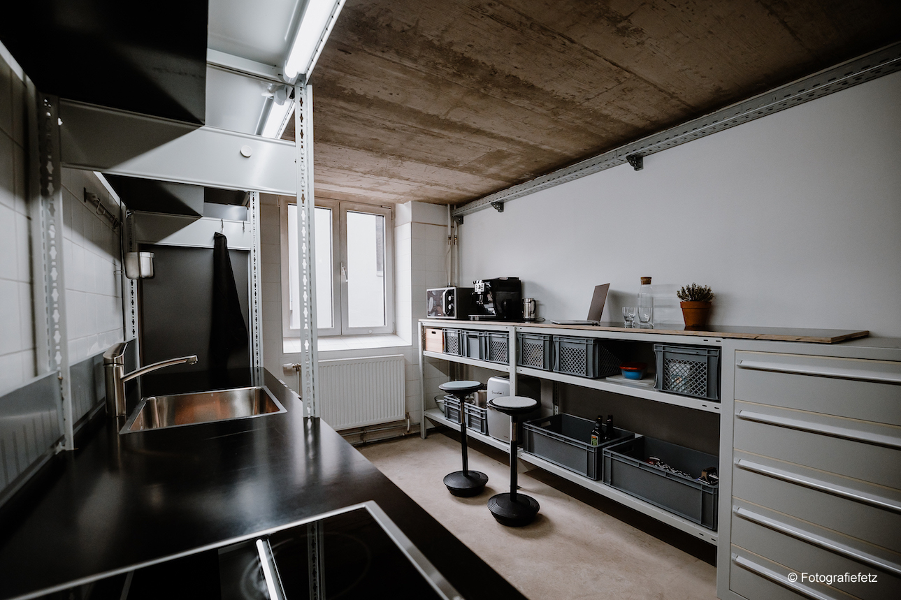 An office kitchen with two Stitz.The kitchen and the products are in shades of gray and black.