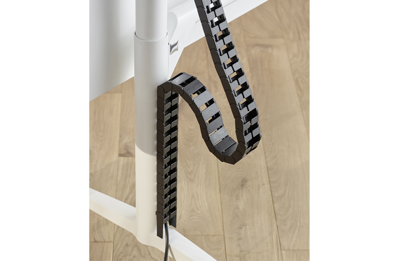 A close-up of a black cable system on a white Timetable table leg.