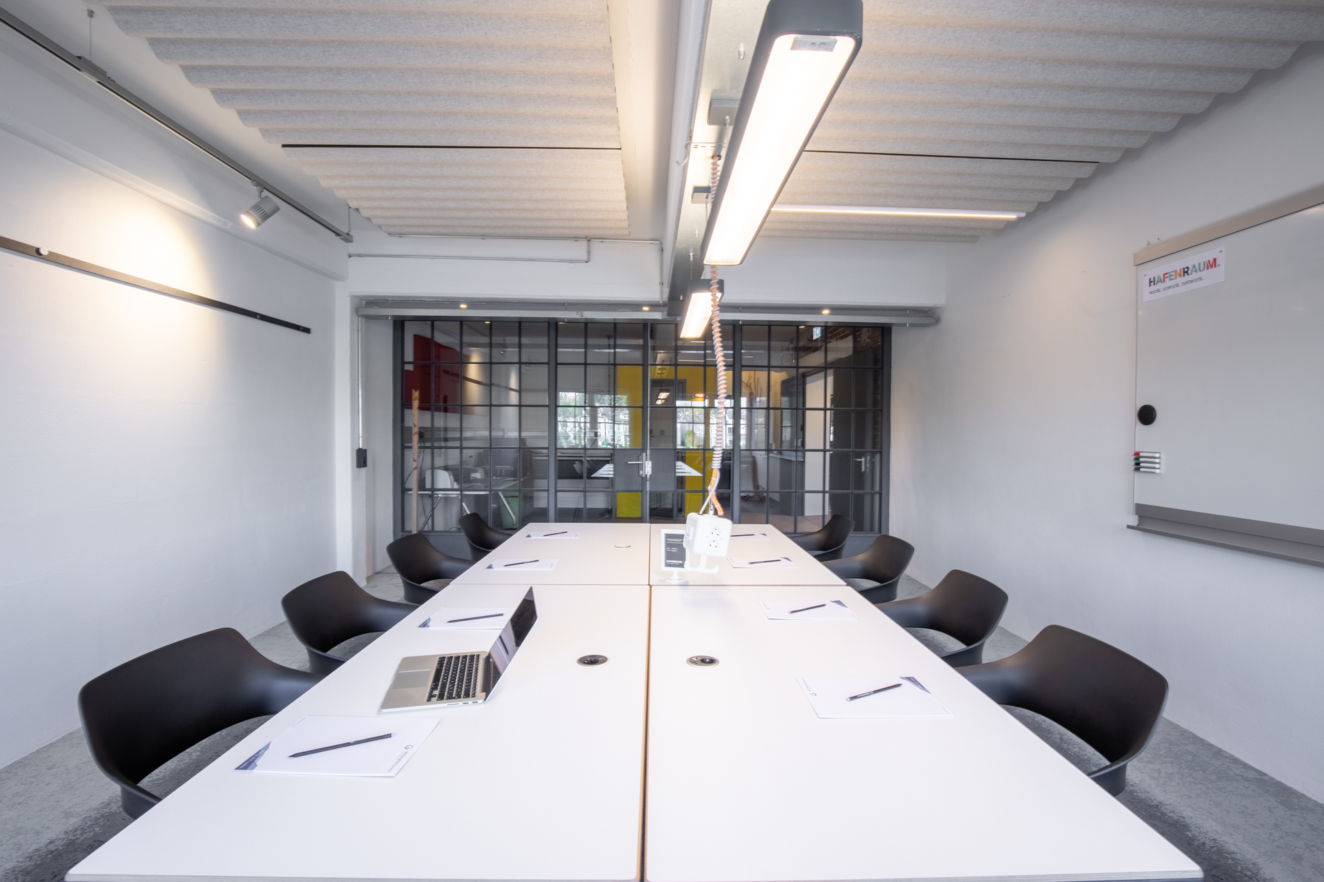 A view of a conference room with four white Timetable tables and eight black Occo chairs without upholstery.