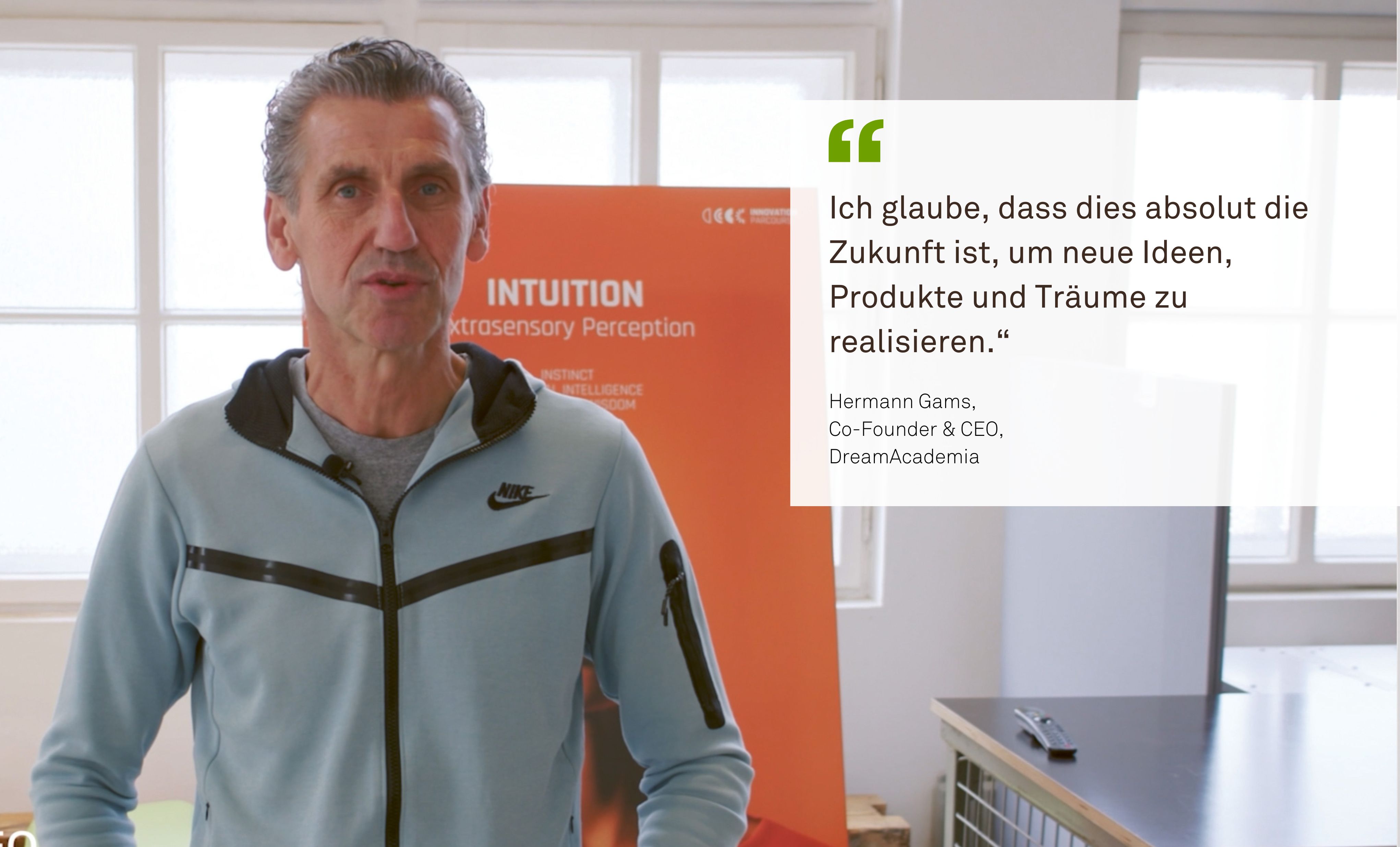 A man named Hermann Gams, co-founder and CEO of DreamAcademia, stands in a bright room in front of an orange display. Next to him is his quote: “I believe this is absolutely the future for realizing new ideas, products, and dreams.”