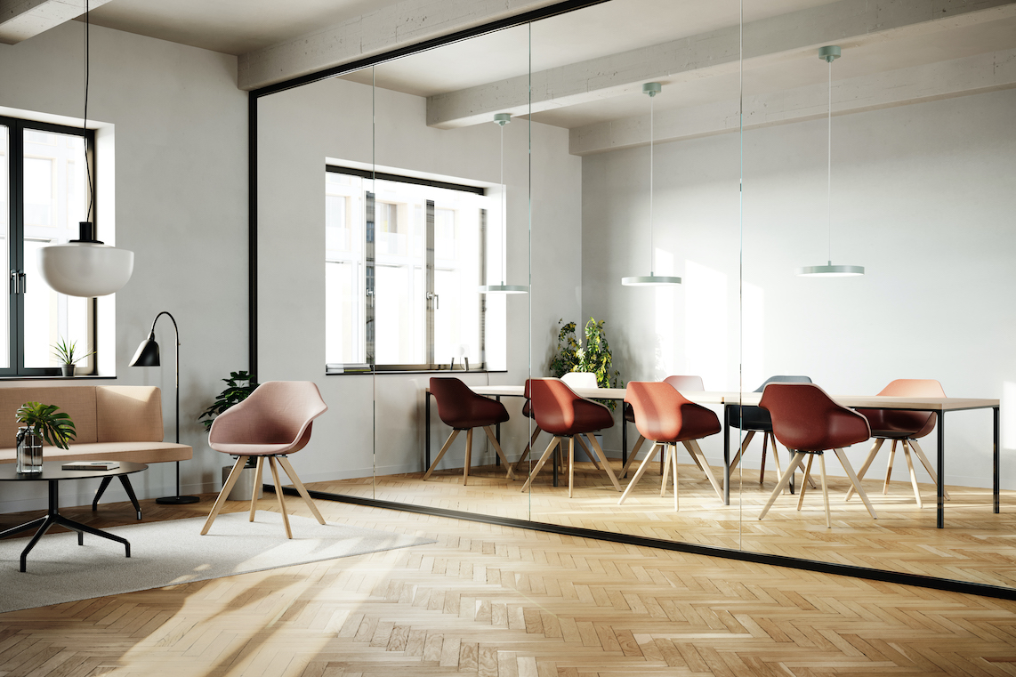 The meeting room is open, flooded with natural light, and features warm wooden accents. Surrounding the table are several Yonda chairs with wooden frames and red seat shells.