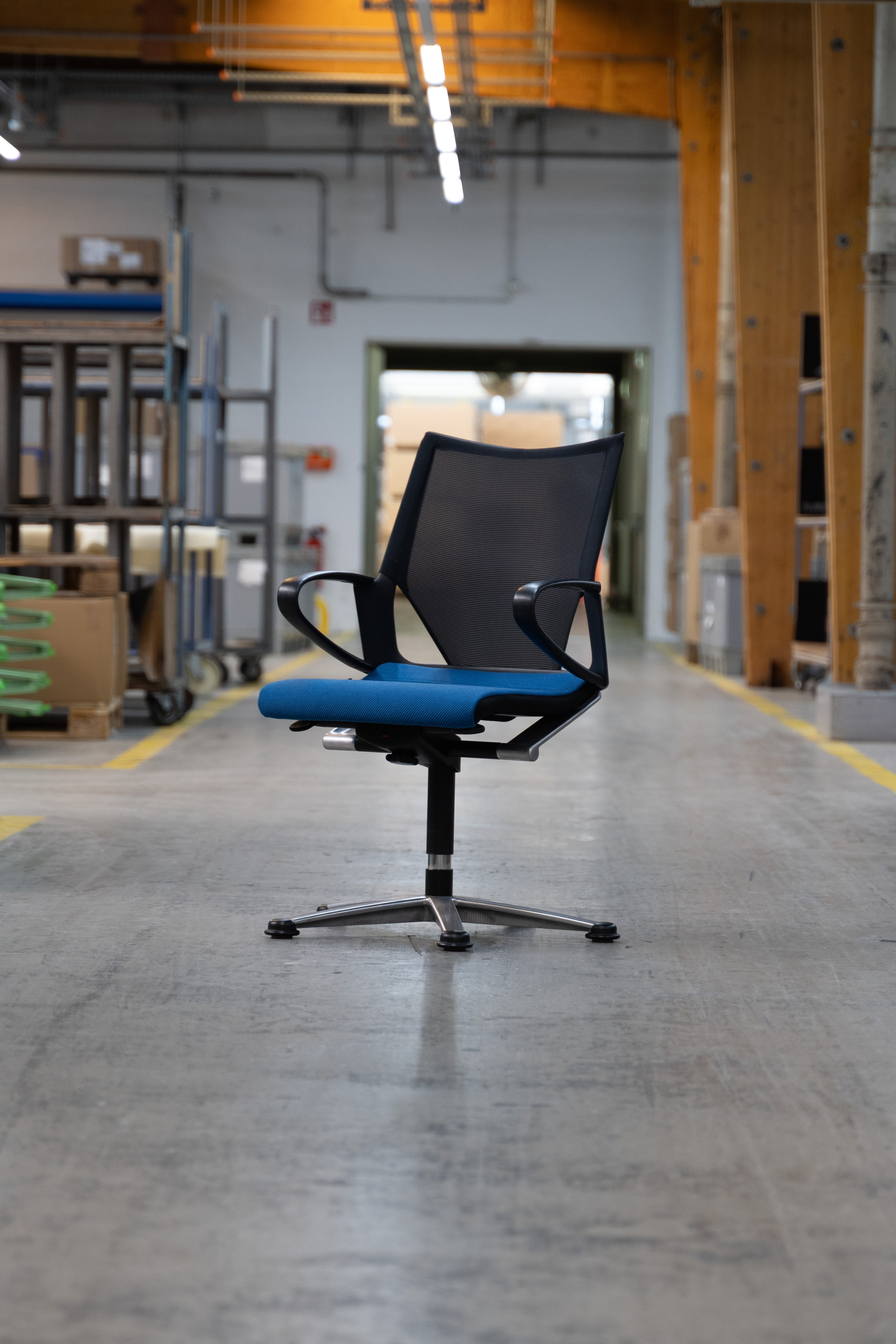 A Modus chair stands alone in the assembly hall. The back is black and the seat upholstery is blue.